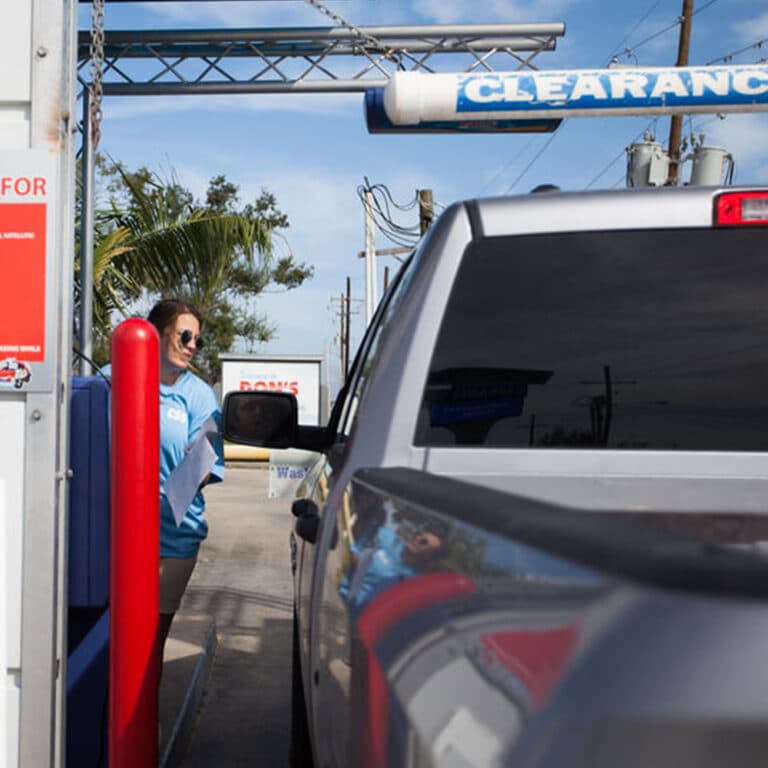 A Don's attendant welcoming a customer at the wash entrance